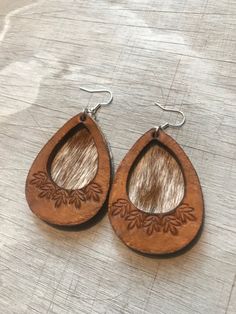 I'm so excited to bring y'all these hand tooled, genuine  leather cutout earrings, layered over hair on cowhide . These are chic- meets-western! Each pair is made to order, so pattern variations will occur, but your pair will be very similar to the photos. Finished with sterling silver-plated ear wires. Earring backs are natural gray suede. Approximate length, 3". Thanks for shopping @boholeathercraft ! Follow me on Instagram & Facebook for sneak peaks, updates, and the occasional promo code and Everyday Hand Tooled Leather Jewelry, Everyday Hand-tooled Leather Jewelry, Brown Leather Teardrop Jewelry, Hand Tooled Brown Earrings For Everyday Wear, Hand Tooled Brown Dangle Earrings, Brown Hand Tooled Dangle Earrings, Handmade Southwestern Brown Jewelry, Brown Hand Tooled Everyday Earrings, Artisan Brown Hand Tooled Earrings