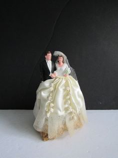 a bride and groom figurine sitting next to each other