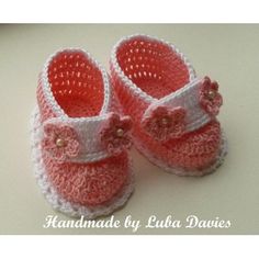 a pair of pink crocheted baby shoes with bows