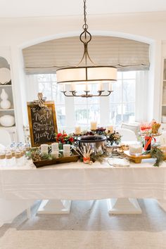 a white table topped with lots of plates and food next to a window filled with windows