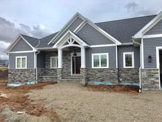 a gray house with white trim on the front and side windows is under construction in this photo