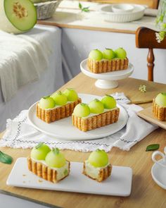 small desserts with green toppings on white plates and serving trays next to each other