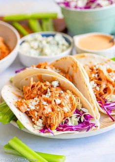 three chicken tacos on a plate with cole slaw and salsa in the background