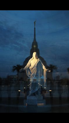 a statue is shown in front of a building at night with lights on the ground