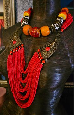 Here's a Bohemian Necklace and Bib Set I found in my inventory. The longer strand is a vintage piece that I did not make. It measures a non-adjustable 28" and closes with a button and a loop. Multiple strands of red-orange seed beads comprise the majority of the piece and two ornate metal accents (looks like bronze) are symmetrically set on each side with an orange-red cabochon (jade??). The shorter necklace is one that I made. It measures a non-adjustable 19" and features the following components: Tibetan resin, Moroccan resin, Zebu bone*, gold tone metal spacers, vintage Chinese brass coins, red branch corals, vintage brass beads and round tiger's eye. Closes with a gold tone hook and eye. Pair them together, or wear separately. These also will mix and match well with your personal favor Vintage Style Polished Beads Necklace, Bohemian Polished Beads Jewelry For Festival, Vintage Hand-strung Beaded Necklaces For Festivals, Hand-strung Necklaces For Festivals, Vintage Hand-strung Beaded Necklace For Festivals, Adjustable Vintage Beads For Festival, Vintage Multi-strand Beaded Necklaces, Vintage Adjustable Beaded Necklaces For Festivals, Adjustable Vintage Necklace For Festivals