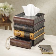 a stack of books sitting on top of a table next to a tissue dispenser