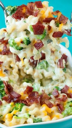 broccoli and bacon macaroni salad is being lifted from a white bowl