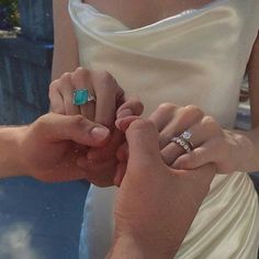 the bride and groom are holding hands with their wedding rings on their fingers while they hold each other's hand