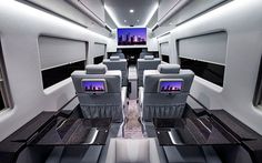 the inside of an airplane with seats, tables and televisions on each side of it