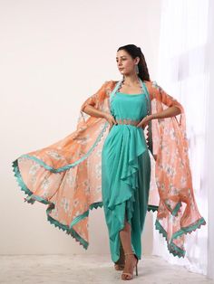 Our custom 'Sakura' print is thoroughly inspired by the overwhelming beauty of the elusive pink flower on the Japanese geometrical patterns bringing together the Japanese and Indian culture. Featuring a teal draped dress with an embroidered belt. It is paired with a printed coral silk organza cape enhanced with color block details. Perfect for destination beach wedding party or bridesmaid outfits! Fabric Composition: Crepe, Organza Care Instruction: Dry Clean Only. Do not use heavy Iron Draped Dress Indian, Festive Dresses With Floral Print And Cape Sleeves, Festive Floral Print Dress With Cape Sleeves, Pink Spring Dress With Traditional Drape, Pink Traditional Drape Dress For Spring, Traditional Pink Dress For Spring, Green Summer Dresses With Cape Sleeves, Green Summer Dress With Cape Sleeves, Green Dress With Traditional Drape