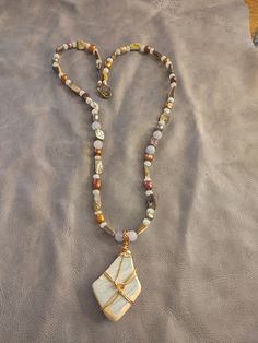 This necklace features a beautiful shard of surf tumbled pottery found on a beach in Puerto Rico. It is wrapped in brass colored copper wire. The beads are AAA quality aquamarine, abalone shell and dyed freshwater pearls. Wire Wrapped Long Necklace In Spiritual Style, White Amulet Jewelry For Meditation, Earthy Beaded Pendant Jewelry, Bohemian Pendant Jewelry For Meditation, White Bohemian Pendant Jewelry, White Bohemian Necklace For Gifts, White Bohemian Necklace As A Gift, White Bohemian Necklace For Gift, Gold Hand Wrapped Necklaces For Meditation