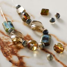 several different colored glass beads on a marble counter top with rusted metal and rusty paint