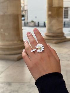 This handmade adjustable ring features a charming white daisy design, meticulously crafted to capture the essence of a blooming flower. The daisy petals are delicate and smooth, surrounding a golden coloured center that adds a touch of elegance and sparkle. The ring band, designed to look like a daisy stem, wraps comfortably around the finger, completing the floral theme.  Perfect for nature lovers and those who appreciate unique, artisanal jewelry, this ring brings a fresh and whimsical touch t White Daisy-shaped Jewelry For Spring, White Daisy-shaped Spring Jewelry, Spring White Birth Flower Jewelry, Adjustable Flower Ring For Spring Anniversary, Spring Anniversary Adjustable Flower Ring, White Flower Jewelry With Sunflower Design, White Flower-shaped Jewelry With Sunflower Design, White Sunflower Design Flower Jewelry, White Flower Ring For Spring