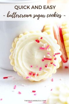 two sugar cookies with sprinkles in front of a white cup and corn on the cob