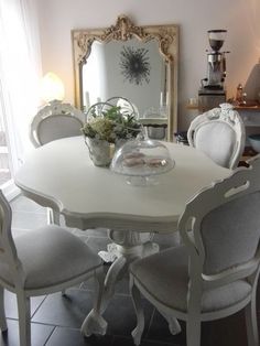 a dining room table with white chairs and a large mirror on the wall above it