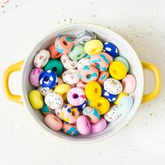 a white bowl filled with lots of different colored doughnuts on top of a table