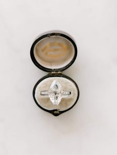 an engagement ring with a large diamond in it's box on a white surface