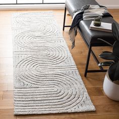 a large white rug on top of a hard wood floor next to a black chair