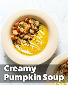 two bowls of creamy pumpkin soup with croutons