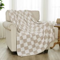 a couch covered in a checkered blanket next to a table with a potted plant