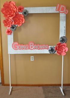 a photo frame decorated with paper flowers and the words going brown on it is sitting in front of a wall