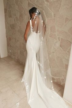 a woman in a wedding dress with a veil over her head and flowers on it