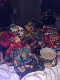 a pile of food sitting on top of a bed next to a bag of chips