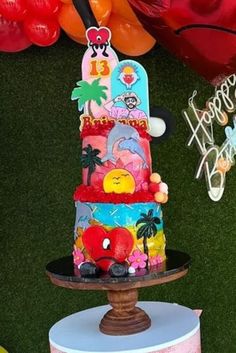 a multi - tiered cake is decorated with cartoon characters and balloons in the background