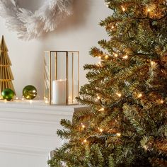 a lit christmas tree next to a fireplace mantel with candles and ornaments on it