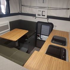 the interior of a small boat with wooden tables and black chairs on either side of the table