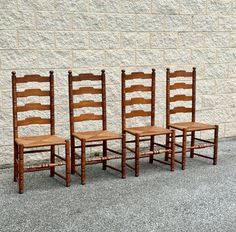 three wooden chairs sitting in front of a brick wall