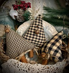 three cloth hats are sitting in a basket with pine branches and other holiday decorations behind them