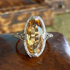 Details: Beautiful Vintage Marquise Citrine set in white 14K gold with filigree and engraving along the setting. The citrine has a gorgeous warm golden orange color. The interior has a 14K stamp. Please ask all necessary questions prior to placing an order. Measurements: The size is 5 1/2 US and can be sized for a fee. The marquises stone measures 14mm x 7mm. The weight of this ring is 2.8 grams. Condition: The overall all condition of this ring is excellent. The citrine is intact and securely s Elegant Orange Topaz Ring, Elegant Orange Topaz Ring In 14k Gold, Elegant Formal Orange Topaz Ring, Ornate Yellow Gold Filigree Ring With Gemstone, White Gold Citrine Topaz Wedding Ring, Antique Orange Rings For Formal Occasion, Orange Victorian Jewelry For Formal Occasions, Victorian Filigree Ring With Gemstone In Yellow Gold, Victorian Yellow Gold Filigree Ring With Gemstone