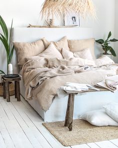 a bed with pillows and blankets on top of it in a room next to plants