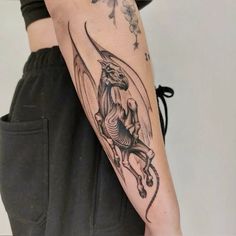 a woman's arm with a dragon tattoo on the left side of her body