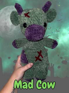 a hand holding a stuffed animal in front of a green background with the words mad cow on it