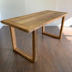 a wooden table sitting on top of a hard wood floor next to a brick wall