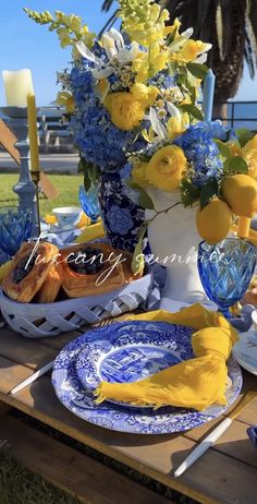 a table with blue and white plates, yellow flowers and lemons