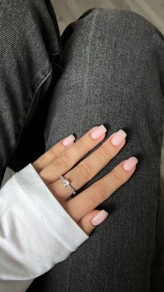 a woman's hand with pink and white nail polish on her nails, sitting on the couch