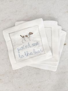 three napkins with embroidered words on them sitting on top of a white countertop