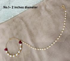 a white beaded bracelet with red beads and a gold plated clasp on it