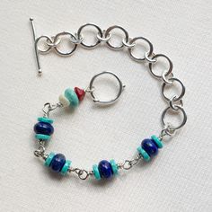 Looking for your new go-to piece? You've found it. Bright Lapis Lazuli sandwiched between slices of equally vivid Turquoise with a quirky contrasting link featuring Mother of Pearl, Coral and more Turquoise - Phew! All on a sinuous fine silver chain. Not for the shy retiring type, this luxurious bracelet will bring smiles every time it's worn, not to mention compliments on your great style. Each circle link is made by hand in fine silver which is a pure metal and will resist tarnish more than st Handmade Turquoise Multi-strand Bracelets, Silver Lapis Lazuli Bracelet, Hand-strung, Unique Nickel-free Turquoise Bracelet, Elegant Turquoise Multi-stone Bracelets, Turquoise Ocean-inspired Bracelet With Lobster Clasp, Lapis Jewelry, Colorful Jewelry, Layered Bracelets, Bracelet Gift