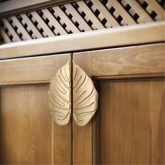 a wooden cabinet door with a carved leaf on it