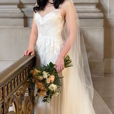 a woman in a wedding dress standing on a balcony with her veil over her head