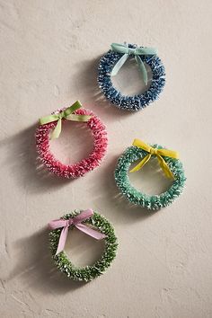 three different colored bracelets with bows hanging from the side on a white wall next to each other