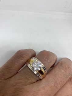 a man's hand with a gold and white ring on his left hand, in front of a white background