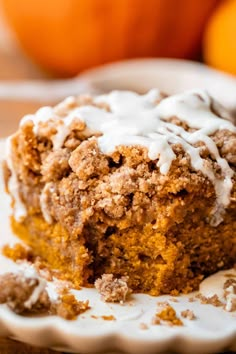 a close up of a piece of cake on a plate with icing and oranges in the background