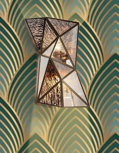 a mirror hanging from the side of a wall next to a green and gold pattern