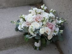 a bouquet of white and pink flowers sitting on the steps