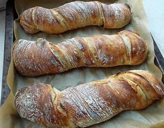 three loaves of bread sitting on top of a baking pan next to each other